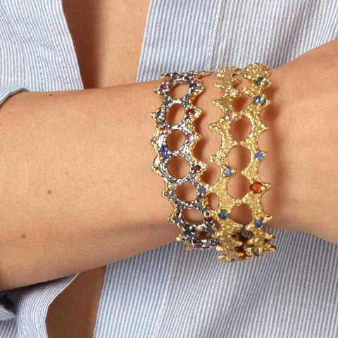 Sterling silver and 18k gold bangle bracelets with colored sapphires on a models arm by Jane Bartel Jewelry