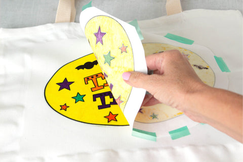 Peeling back the sublimation design paper from heat transfer tote bag 