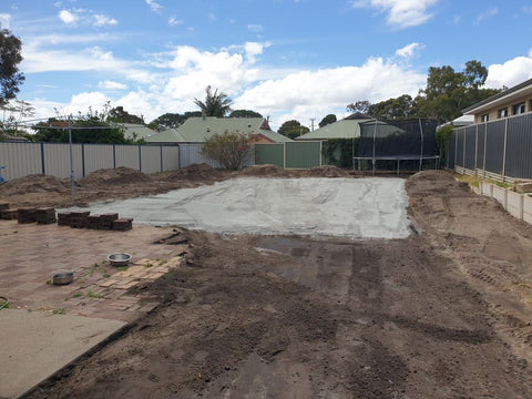 Backyard in the middle of renovations. Entire backyard is dirt, except for a concrete square in the middle.