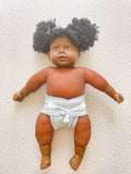 dark skined doll with a green preflat cloth nappy on