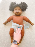 dark skined doll laying on a green preflat cloth nappy