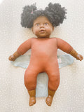 dark skined doll laying on a green preflat cloth nappy