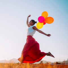 Carefree woman with balloons in a field