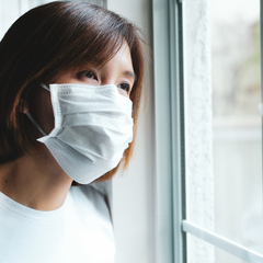 woman with face mask looking out the window