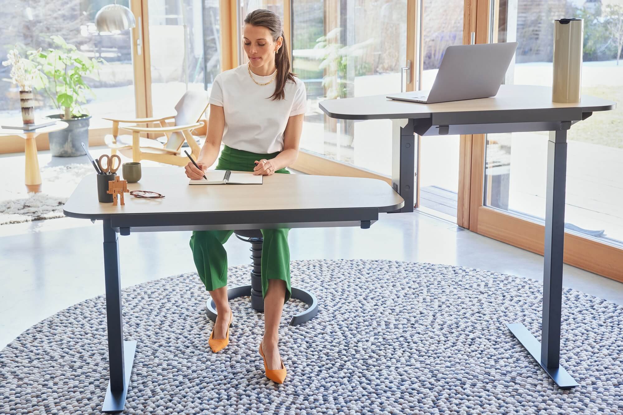 Vrouw zittend op de ergonomische bureaustoel Aeris Swopper aan het in hoogte verstelbare bureau Aeris Active Office Desk