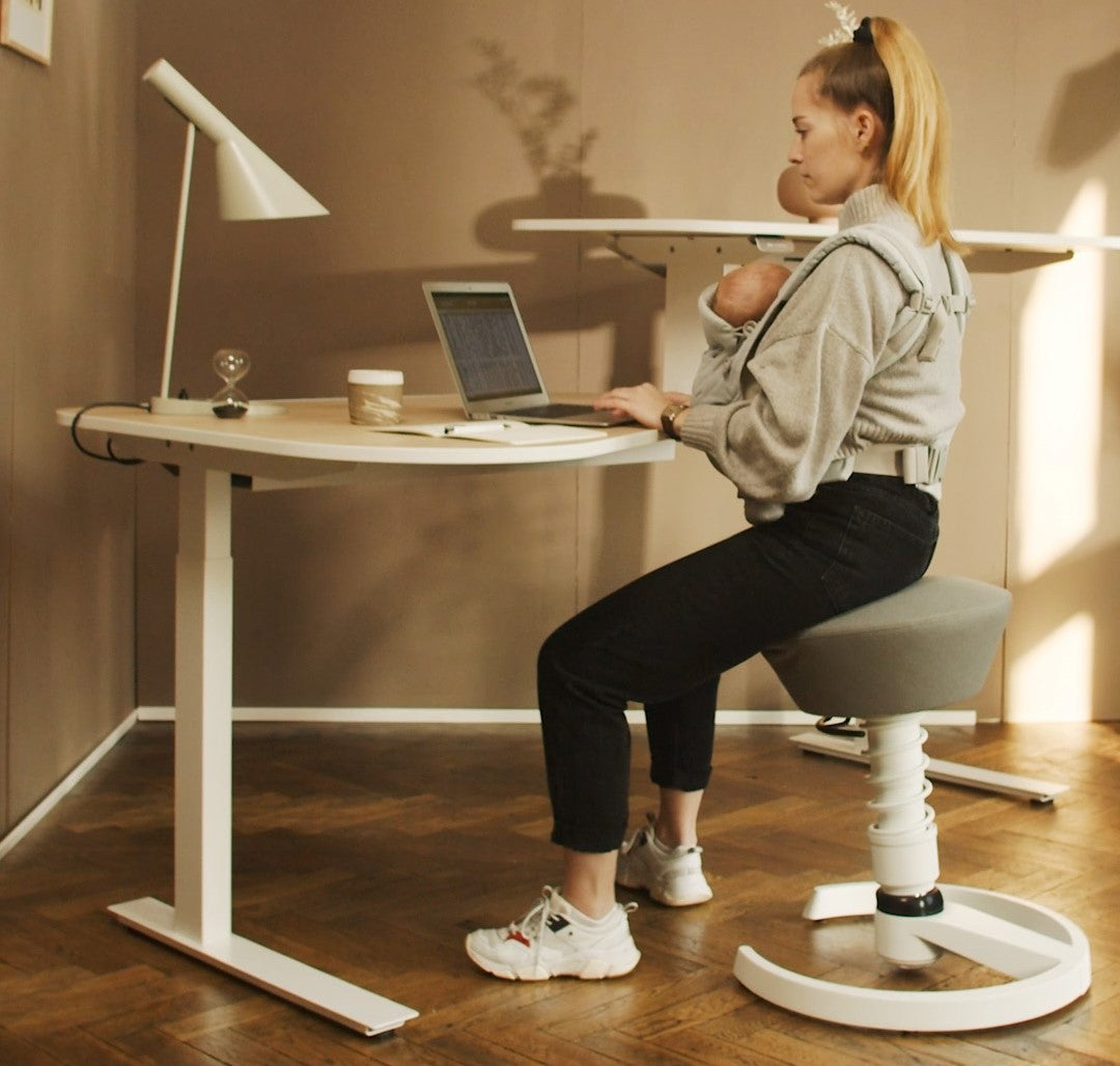 Femme assise avec un bébé sur une chaise de bureau ergonomique Aeris Swopper