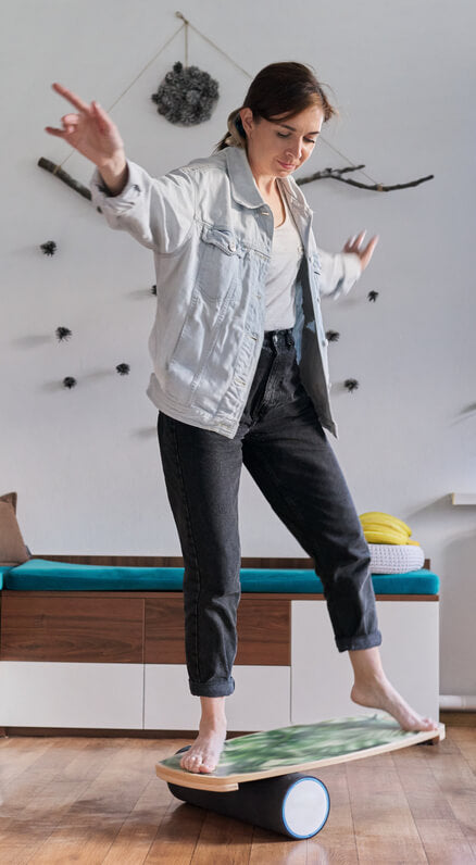Must-haves voor het thuiskantoor: balansbord. Een vrouw oefent thuis op de evenwichtsbalk.