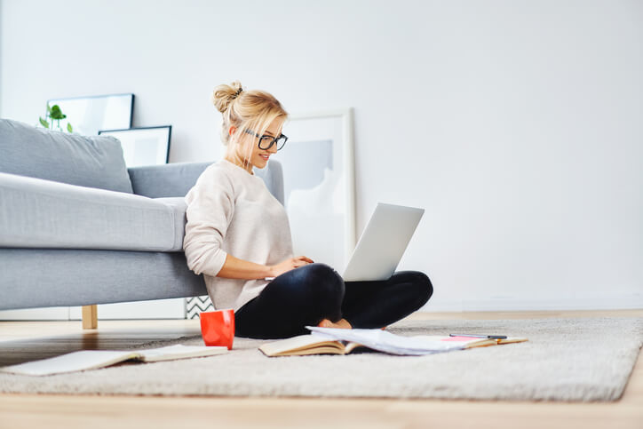 Falsche Haltung und Bewegungsmangel im Home-Office. Frau sitzt auf dem Boden und arbeitet.