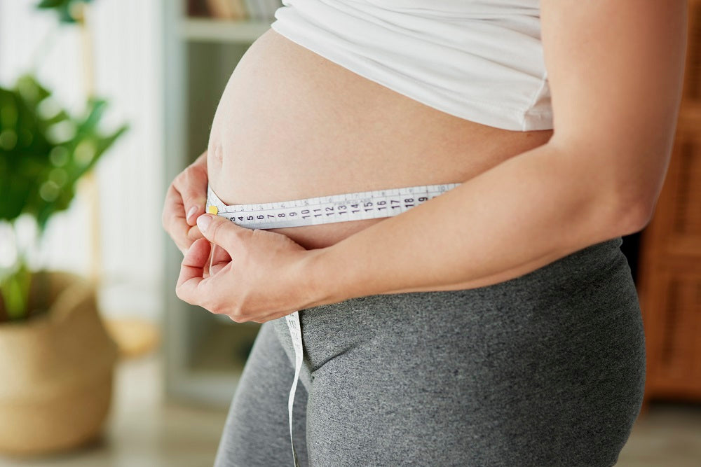 Woman measuring her belly circumference during pregnancy