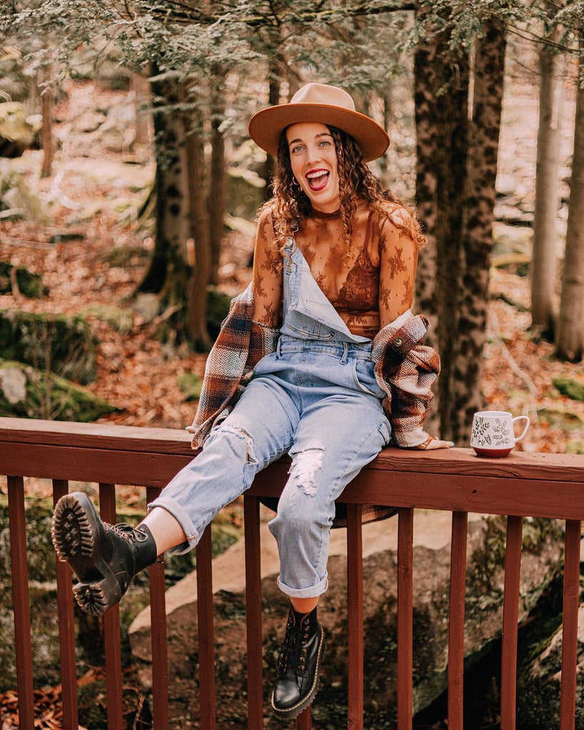 Dani sitting on a railing wearing the campfire button down