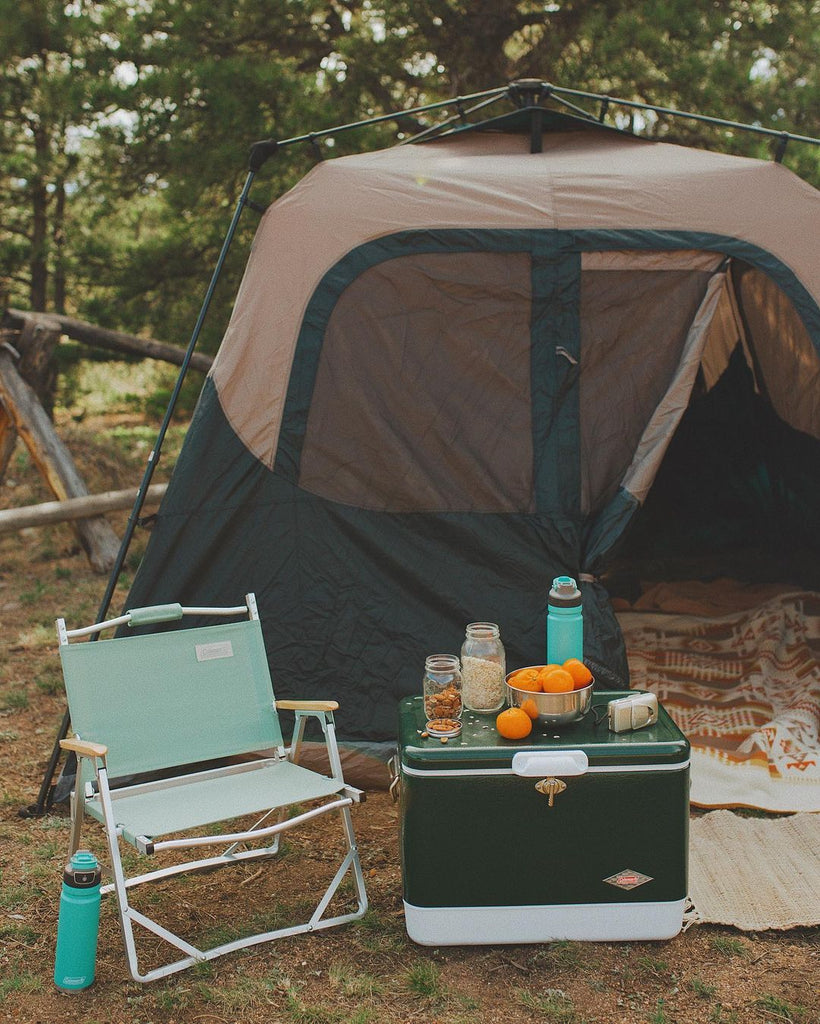 A tent set up with a cooler and camp chair