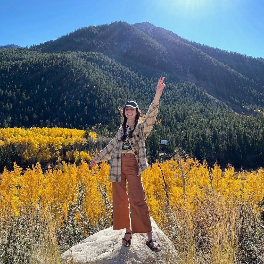 Rachel standing in front of mountains surrounded by yellow aspen trees