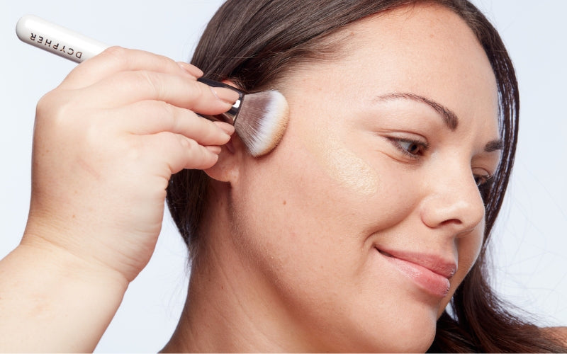 Model applying foundation with a brush