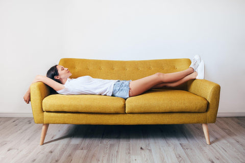 Happy young woman lying on couch and relaxing at home