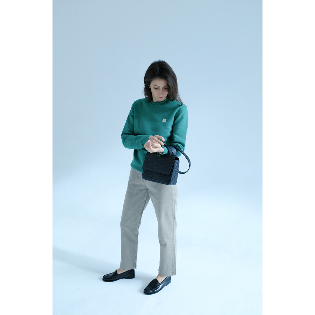 Woman wearing a green sweatshirt with chinos, leather loafers and a leather bag