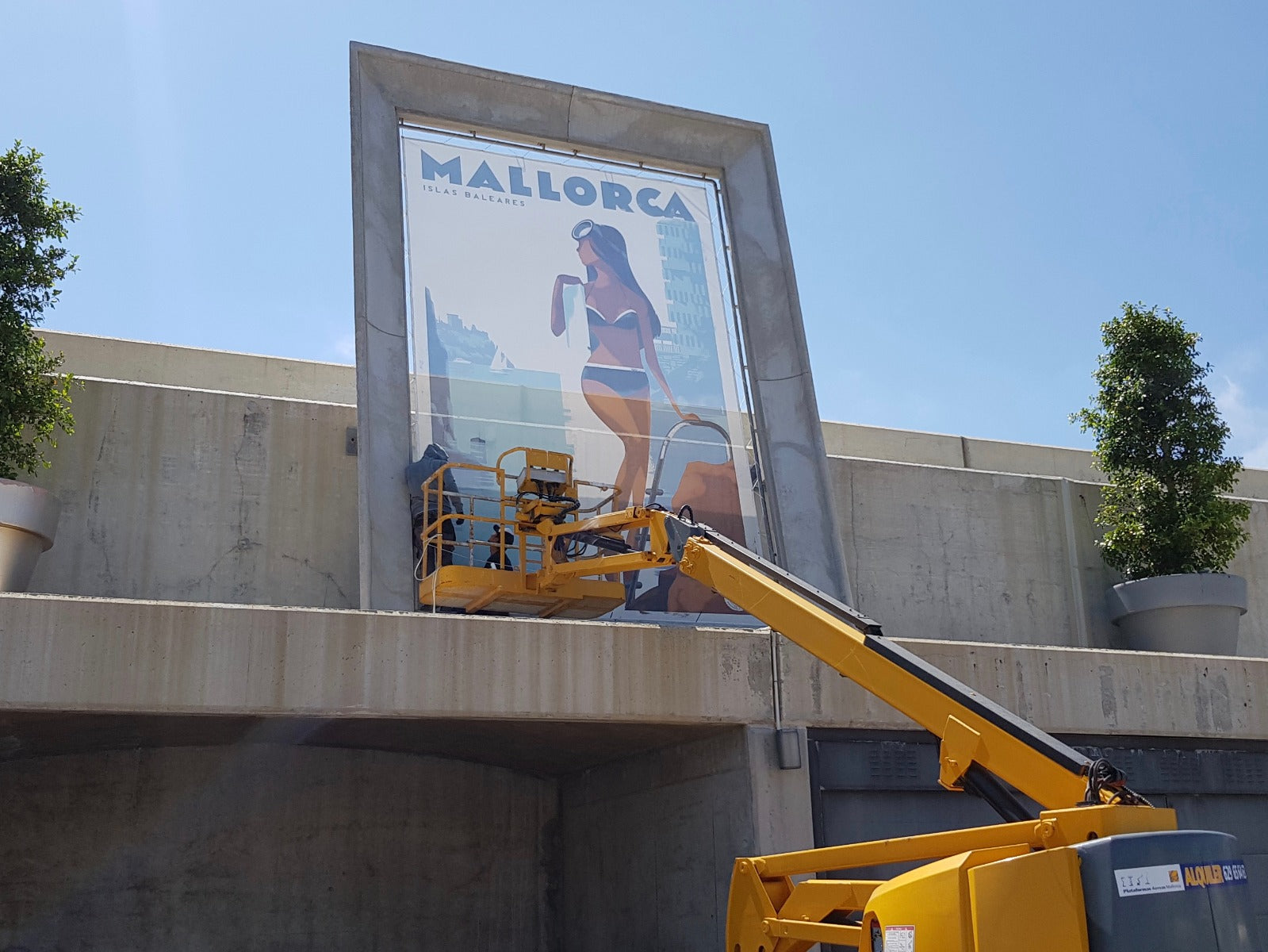 Crane putting up  industrial scale / giant version of La Nadadora poster on either an airtex type perforated material or flex as per this Philippe Starck-framed 5 x 3 metre example