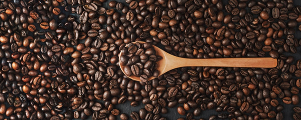Coffee Beans with A Wooden Spoon Sifting Through