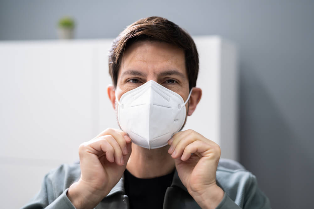 Man adjusting fit of KN95 face mask over beard