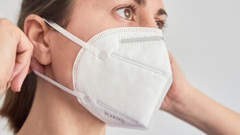 Woman gently removing KN95 mask loops from around ears