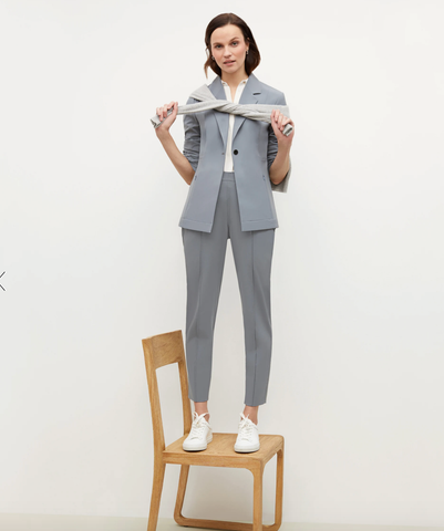 woman in grey blue blazer and slacks standing on chair