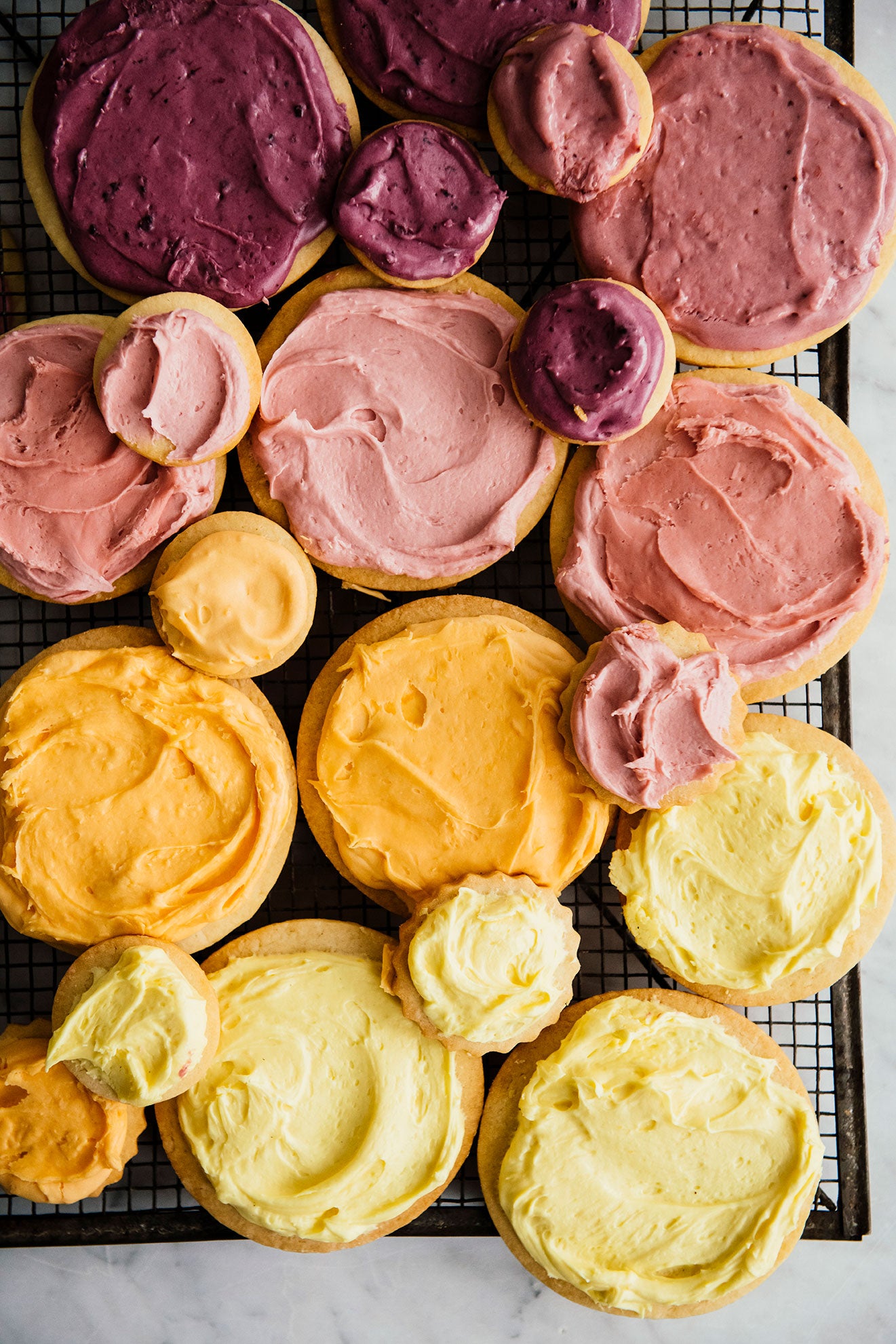 round sugar cookies frosted in yellow, orange, pink, and purple