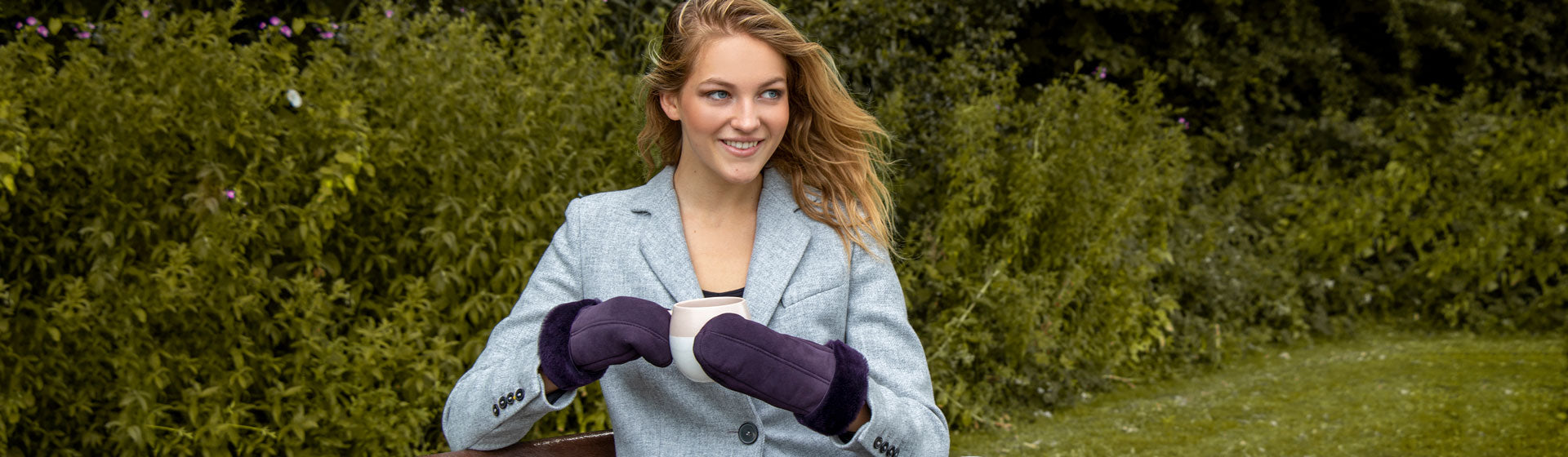 Woman wearing sheepskin mittens in plum at the park