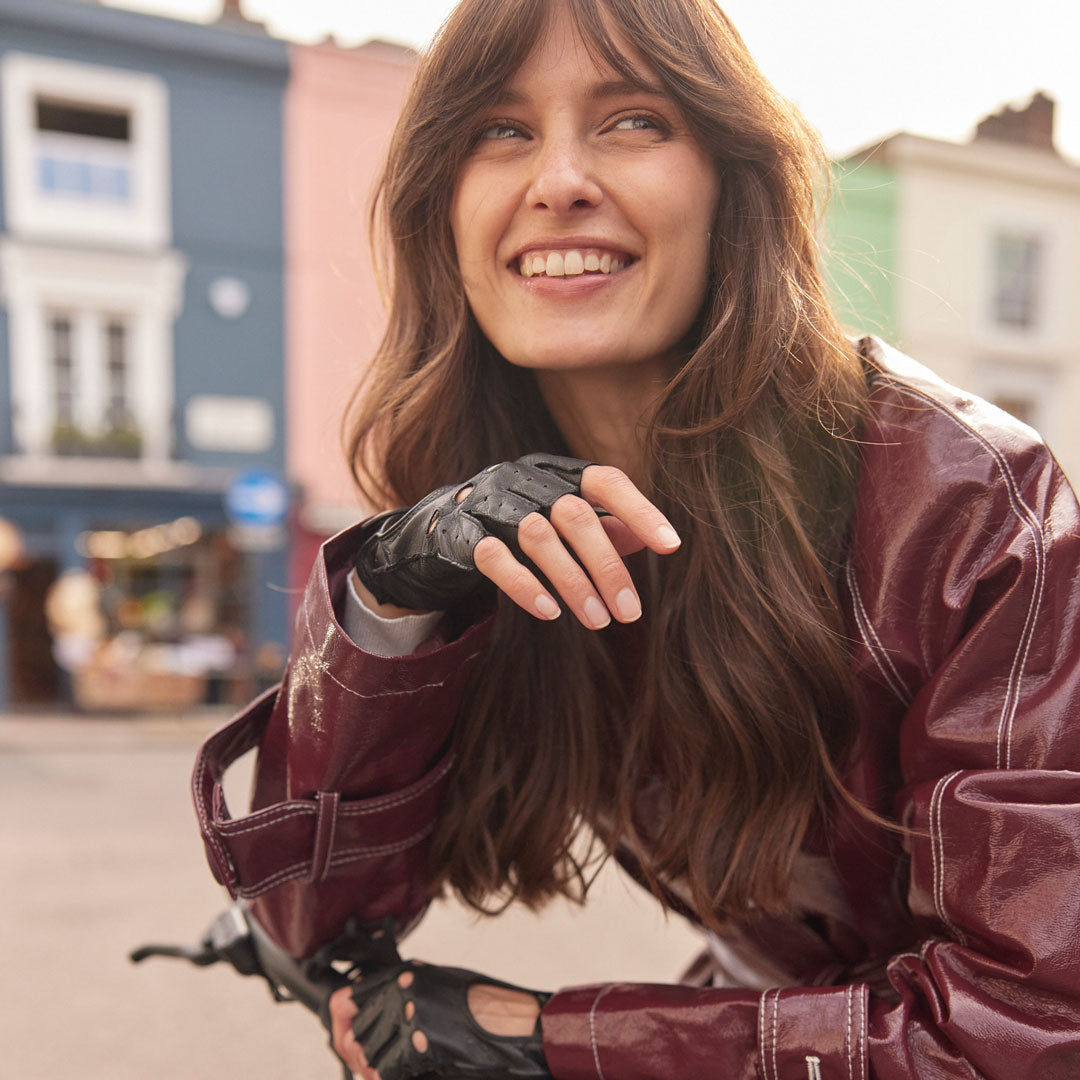 Woman wearing fingerless leather driving gloves in black