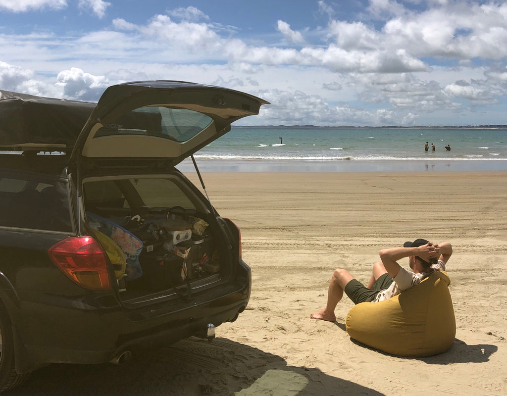 Andy Bowie relaxing next to car at beach