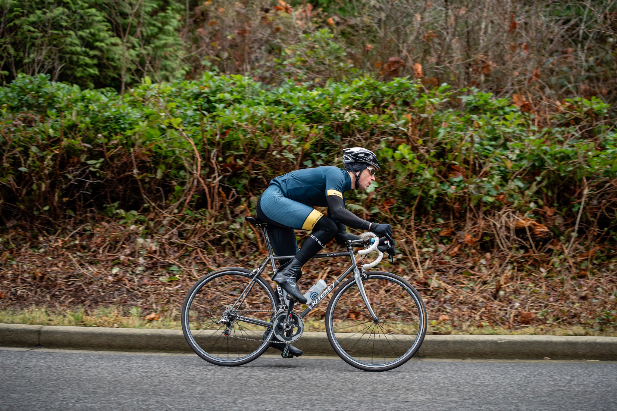 Cyclist in a Blonyx jersey riding quickly on a treed road