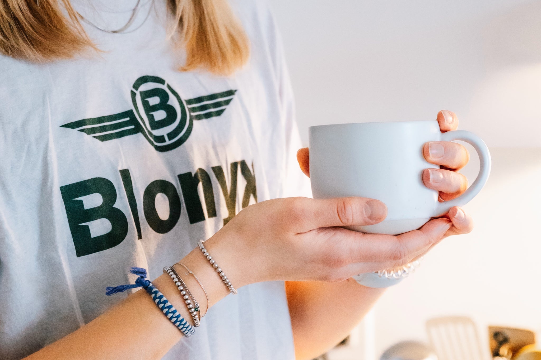 Woman in a Blonyx tee shirt holding a cup of coffee