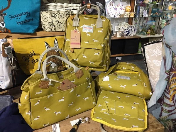 Photo of a selection of mustard coloured Brakeburn bags with sausage dog print.