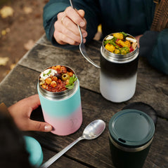 Lifestyle photo of two people sitting at a picnic bench eating out of two, 500ml Chilly's food pots. Only their hands and the food pots on the table can be seen.