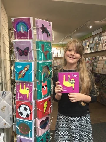Photo of Eden standing next to a spinner of Redback's Shine range of cards