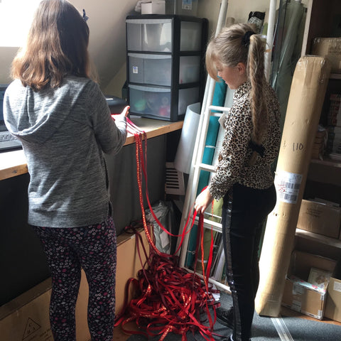 Photo of two girls in the shop stock room printing ribbon.