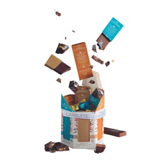 A hexagonal cardboard box is open with chocolate bars and individual chocolates exploding out of it. It is possible to see inside some of the bars to see the rocky road elements.