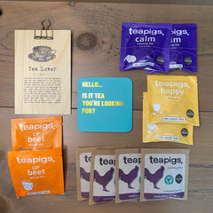 Tea Drinker Letterbox Gift Set comprising of a range of individually wrapped teabags, a humorous coaster and a wooden sign with lots of quotes about tea on it.