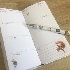 Photo of the 2019 Wrendale Designs slim diary opened up to a double page spread. A Wrendale pen is sitting on top of the diary.