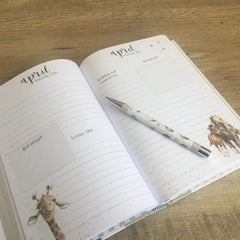 Photo of the 2019 Wrendale Designs desk diary open on a double page spread. A Wrendale pen is sitting on top.