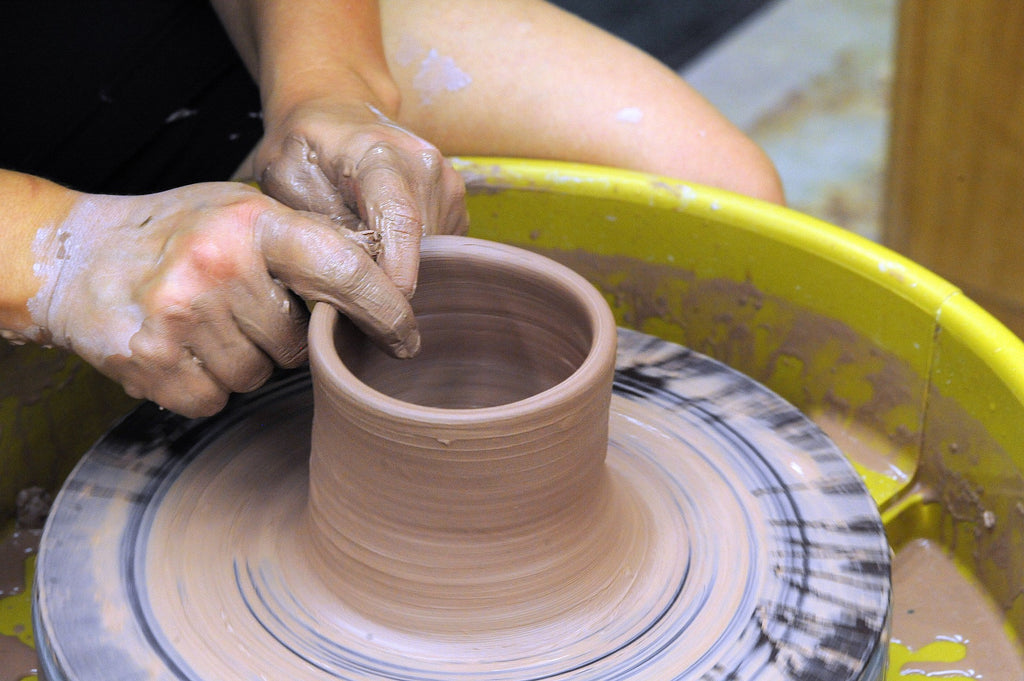 Potter moulding clay on pottery wheel