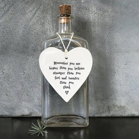 porcelain heart hanging on glass bottle, the heart is engraved with 'remember you are braver than you believer, stronger than you feel and smarter than you think'