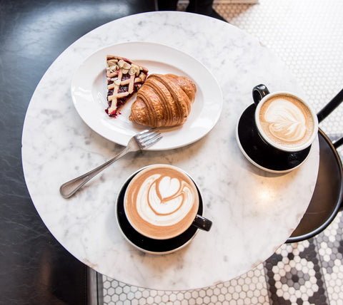 a round table with a plate of pastries and two coffee cups