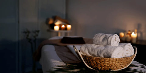 a dark room, lit by candles with rolled towels and a massage bed