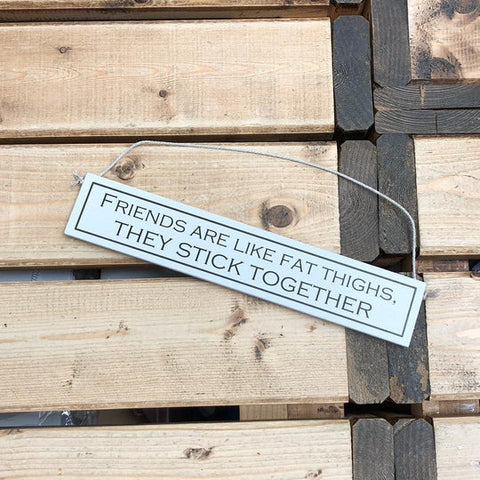 a wooden sign on a wooden background. the sign reads 'friends are like fat thighs, they stick together'