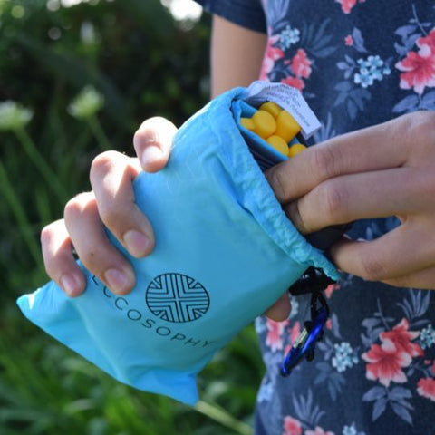 An ECCOSOPHY compact and lightweight pocket blanket which is 60x55 inches when laid out. It is folded in to its travel pouch with a matching carabiner and four ground pegs which hold it in place when it is laid on the grass. This blue waterproof  ECCOSOPHY pocket blanket is ideal for college students.