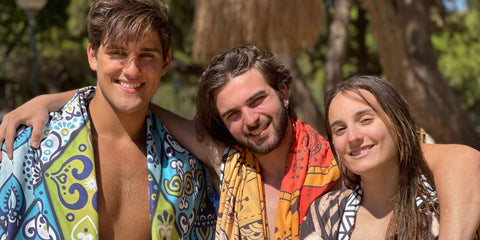 3 ECCOSOPHY models on a greek beach with quick dry and sand free microfiber beach towels wrapped around their shoulders 