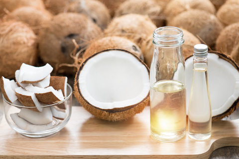 a bottle of coconut oil sits infront of coconuts