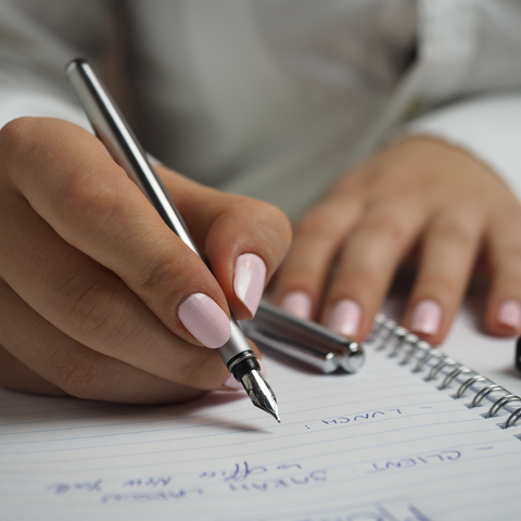 a person writes in a notebook with a pen