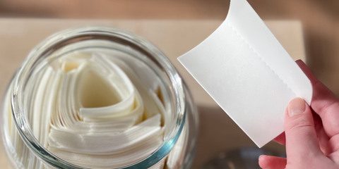 a hand holds a laundry strip above a jar full of laundry strips.