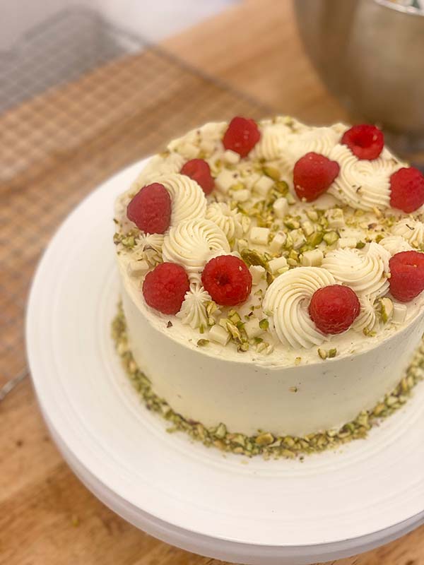 Decorating a simple birthday cake - with raspberries and white chocolate chips and pistachios