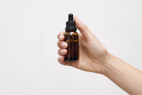 a hand holding a tincture bottle